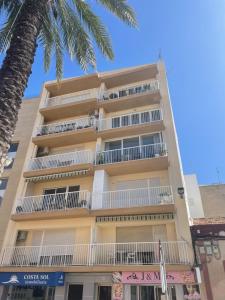 a tall building with white balconies and a palm tree at Central loft apartments in Santa Pola