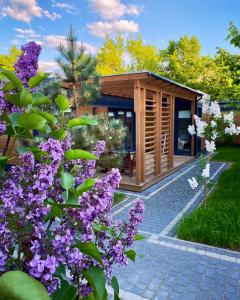 a small wooden house with purple flowers in front of it at Resort 36 in Mikołajki