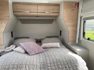 un letto con due cuscini sul retro di una roulotte. di Autocamper Tórshavn a Tórshavn