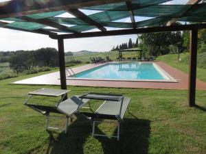 a pool with two chairs and a pergola at Agriturismo Borgo Del Papa in Badia