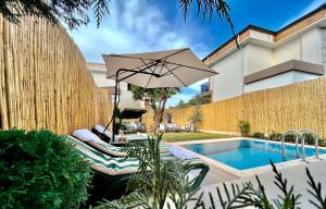a patio with an umbrella and a swimming pool at Seaview Grand - VILLA SUNRISE in Marmaris