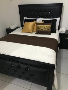 Hato MayorNew Condo Palma Real 3 bd Apt 5 mins from STi的一张带有黑色床头板和枕头的床