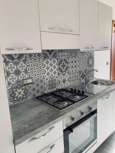 a white kitchen with a stove and a patterned wall at Casa Vacanza Elena in Capo dʼOrlando