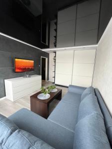 salon z niebieską kanapą i telewizorem w obiekcie Apartament MAKEJA w mieście Malbork