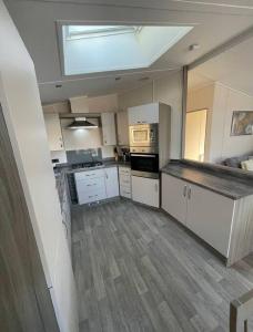 a large kitchen with white cabinets and a skylight at C05 - The Ogwen Lodge with Hot Tub in Bethesda