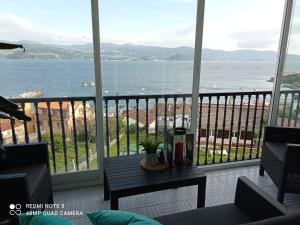 een balkon met een tafel en uitzicht op de oceaan bij Apartamento con vistas en Raxó in Raxo