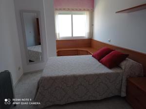 Apartamento con vistas en Raxó في راكسو: غرفة نوم بها سرير ووسادتين حمرا