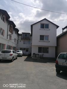 a white building with cars parked in a parking lot at Perfekte Rast in Sibiu