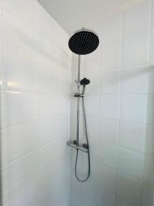 y baño de azulejos blancos con ducha y cabezal de ducha. en Canal apartment at historic CityCenter Amersfoort en Amersfoort