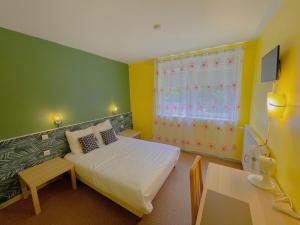 Schlafzimmer mit einem Bett, einem Tisch und einem Fenster in der Unterkunft Hotel Le Ronchamp in Ronchamp