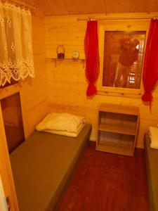 ラダバにあるRadawa Leśne Domki - Leśny domekのベッドと窓が備わる小さな客室です。