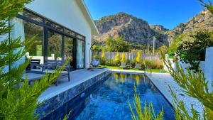 a house with a swimming pool with mountains in the background at Honeymoon Villa in Gocek in Göcek