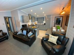 een woonkamer met 2 leren banken en een keuken bij L09 - The Snowdon Spa with Hot Tub in Bethesda
