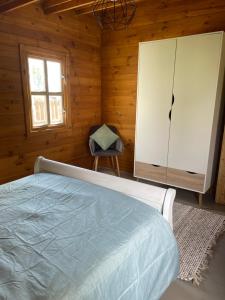 a bedroom with a bed and a chair and a window at DOMAINE DES GALLINACES CHALET SUSSEX 2-4p in Marigny-lès-Reullée