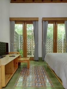 Komoreya Guesthouse في Kejayan: غرفة نوم بسرير ومكتب ونوافذ