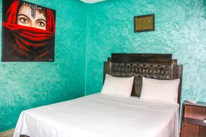 - une chambre avec un lit et une peinture d'une femme dans l'établissement BAGATELLE STUDIO GUELIZ, à Marrakech