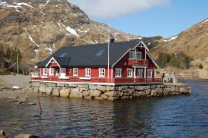 une maison rouge sur une île dans l'eau dans l'établissement Brustranda Fjordcamping, à Valberg