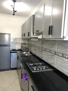 una cucina con armadi bianchi e piano di lavoro nero di T3 beautiful apartment for rent a Martil
