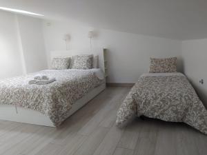 a bedroom with two beds and a wooden floor at Isaura Home in Peniche