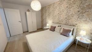 a bedroom with a white bed and a wall at Apulum Apartment in Alba Iulia