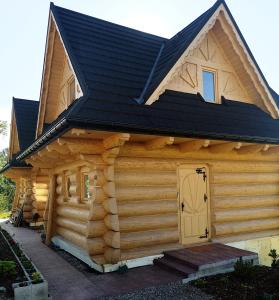 a log cabin with a black roof and a door at Domki Góralskie Dwa Misie in Bukowina Tatrzańska