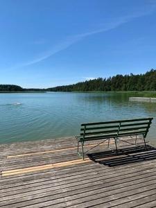 a bench sitting on a wooden boardwalk next to a lake at Zielony Zakątek nad Jeziorem in Danowskie