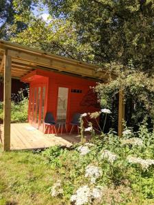 a red shed with two chairs on a deck at Stay Wild Retreats 'Glamping Pods and Tents' in Wrexham