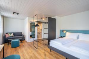 ein Schlafzimmer mit einem Bett, einem Stuhl und einem Sofa in der Unterkunft Hotel Balm in Luzern