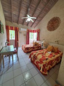 a bedroom with two beds and a ceiling fan at Sea Symphony Villa in Saint Lucy