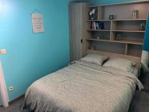 a bedroom with a bed with a blue wall and shelves at Rocroi: Gîte de Bourgogne in Rocroi