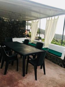 una mesa negra y sillas en un patio con ventanas en Casa Vacanze Oasi di Venere, en Pantelleria