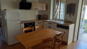a kitchen with a wooden table and a white refrigerator at Le Gîte des Murmures in Urcel