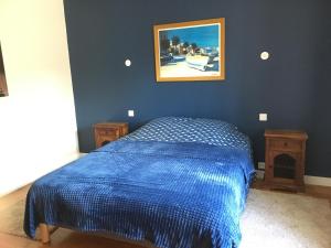 Un dormitorio con una cama azul y una foto en la pared en Le Gîte des Murmures, en Urcel