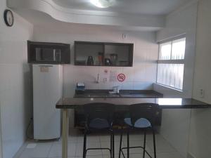 a kitchen with a counter with stools and a refrigerator at SOSSEGO E CONFORTO COM LAZER NA SUA PORTA in Caldas Novas
