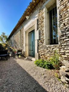 a stone building with a bench and a window at Gîte Douceur de Provence in Maubec