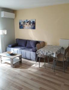 a living room with a blue couch and a table at Bodzafa Apartman in Alsópáhok