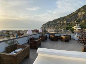 a rooftop patio with tables and chairs and a view of the ocean at La Pennichella Sorrentina Relais in Meta