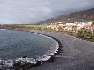 a person standing on a beach next to the water at Caleta de Interian Loft Sasy in Los Silos