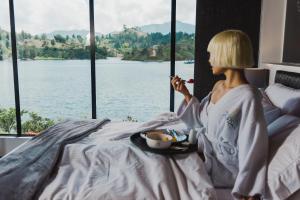 a woman sitting on a bed looking out a window at Jordan Hotel Boutique in Guatapé