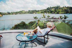 a woman sitting in a chair reading a book at Jordan Hotel Boutique in Guatapé