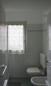 a white bathroom with a toilet and a window at Da Sid in Tremezzo