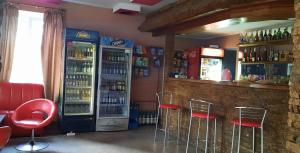 a bar with red stools and a refrigerator with drinks at La Banel Hotel in Selemet