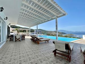 un patio con mesa, sillas y piscina en Villa Meganisi, en Agios Nikolaos