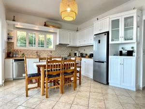Una cocina con gabinetes blancos y una mesa y un refrigerador. en Villa Meganisi, en Agios Nikolaos