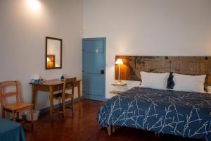 een slaapkamer met een bed, een tafel en een bureau bij Casadangra, bnb in Angra do Heroísmo