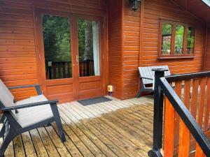 a porch of a wooden cabin with a door and benches at L10 - The Conwy Spa with Hot Tub in Bethesda