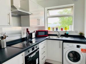 a kitchen with a sink and a washing machine at Spacious and Bright 2 Bedroom Apartment, Sleeps 6, 1st Floor with Free Parking, Business and Leisure by Jesswood Properties in Hinckley