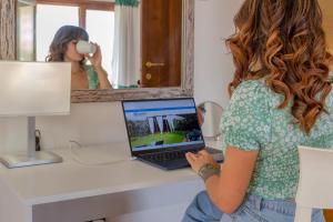 uma mulher sentada numa secretária com um computador portátil em Sardinia Guest House em Olmedo