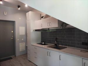 a kitchen with white cabinets and a black tile wall at Cosy Apartments in Vilnius Center in Vilnius