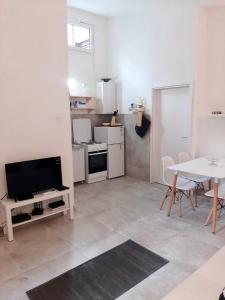 a living room with a tv and a table and a kitchen at Apartment White in Petrovac na Moru